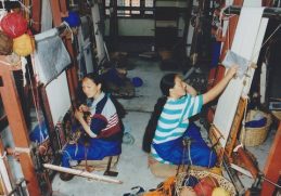 Two women working at carpet looms in Nepal.