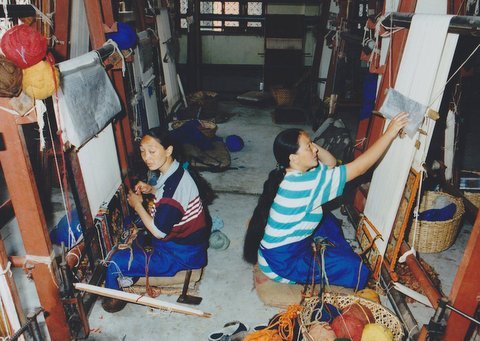 Two women working at carpet looms in Nepal.