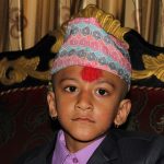 A boy wearing a patterned Dhaka topi.