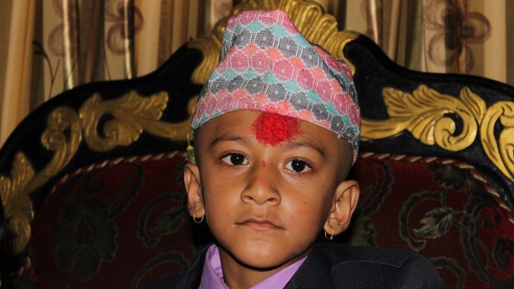 A boy wearing a patterned Dhaka topi.