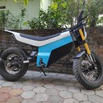 Blue and white Yatri P1 electric motorcycle parked beside a wall.