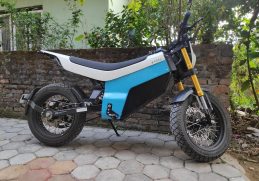 Blue and white Yatri P1 electric motorcycle parked beside a wall.