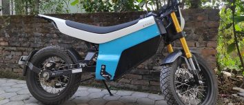 Blue and white Yatri P1 electric motorcycle parked beside a wall.