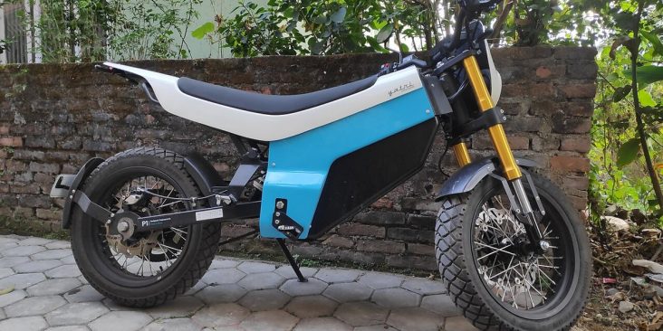 Blue and white Yatri P1 electric motorcycle parked beside a wall.