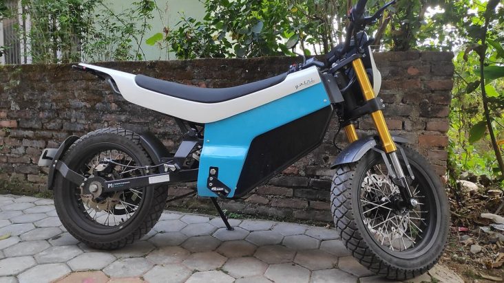 Blue and white Yatri P1 electric motorcycle parked beside a wall.