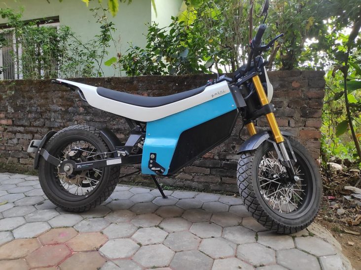 Blue and white Yatri P1 electric motorcycle parked beside a wall.